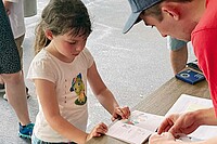 Ein Mann klebt Sticker in das Sammelalbum eines Kindes.