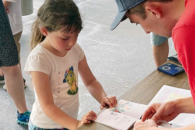 Ein Mann klebt Sticker in das Sammelalbum eines Kindes.