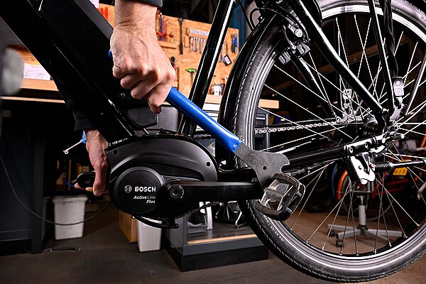 Eine Person zieht die Pedale eines Fahrrad mit einem Pedalschlüssel fest.