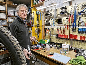 Ein Mann steht in einer Fahrradwerkstatt.