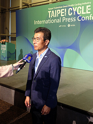 Ein Mann in Anzug und Krawatte spricht in ein Mikrophon.