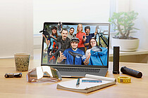 Ein PC-Monitor steht auf einem Tisch, daneben liegt ein Notizblock. 