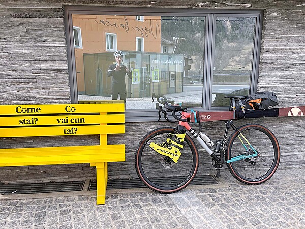 Ski Velo Tour in den Alpen. Fahrrad mit daran befestigten Ski und Skischuhen.
