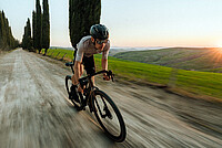 Ein Gravelbiker fährt auf einem Schotter-Weg.