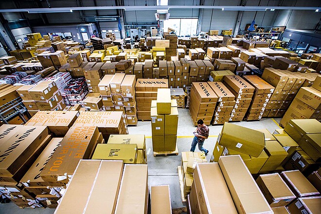 Der deutsche Veloversender Canyon hat zwei neue Investoren an Bord. Ein Mann läuft durch eine Lagerhalle, in der viele Fahrradkartons stehen.