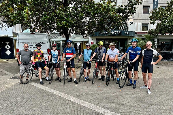 Gruppetto. Radfahrer stehen nebeneinander auf einem Platz.