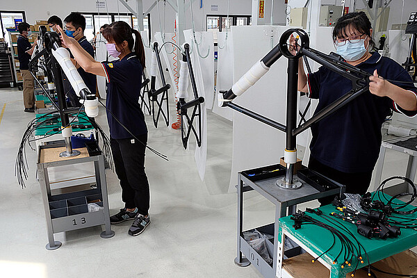 Personen mit Geschichtsmasken montieren Fahrräder in einer Fabrik.