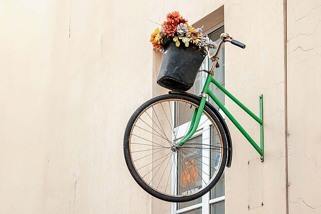 Wie grün ist die Velobranche? Eine neue Studie geht dieser Frage nach. Deloitte Studie Nachhaltigkeit Fahrradindustrie DACH. Ein grünes Fahrrad hängt an einer Mauer.