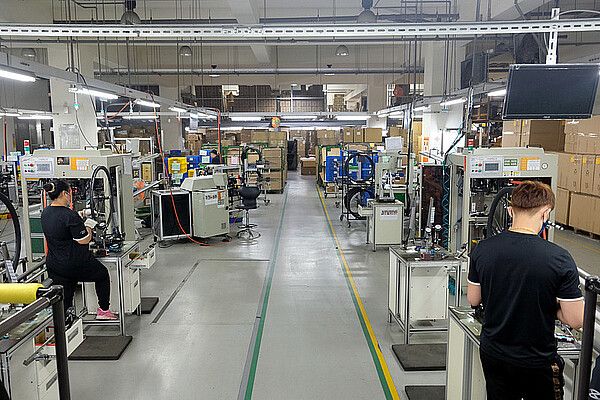 Warum sind die Lager der Velohändler voll. Arbeiterinnen und Arbeiter speichen Fahrradräder ein. 