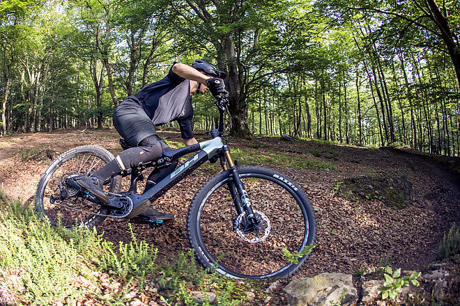 BHZ System by SEG BH Bikes. Ein Mountainbiker fährt auf einem Singletrail im Wald.