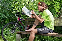 Ein Mann studiert mit einem Kompass in der Hand eine Landkarte