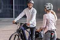 Veloplus Occasions E-Bikes. Ein Mann im weissen Hemd und mit Fahrradhelm sitzt auf einem E-Bike.