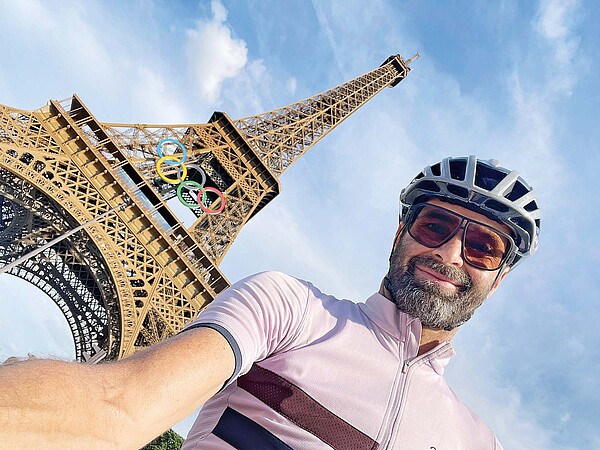 Ein Mann mit Fahrradhelm macht ein Selfie vor dem Eifel Tour in Paris.