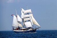 Ein Segelschiff mit weissen Segeln im Meer.