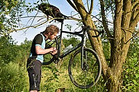 Kettenriss Reparatur so gehts. Ein Mann hat sein Fahrrad an einen Ast gehängt.