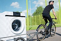 Ein Velofahrer zieht eine Waschmaschine auf dem Anhänger
