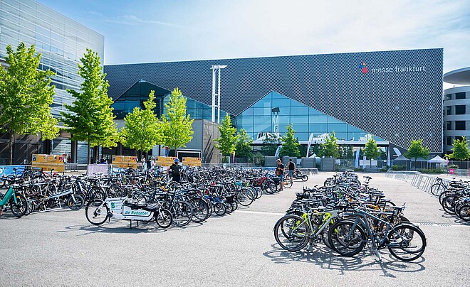 Eurobike 2024. Fahrräder stehen in Fahrradständern vor einer Messehalle.