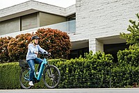 Allride und Rent a Bike gehen Partnerschaft ein. Eine junge Frau fährt auf einem blauen E-Bike.