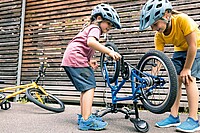 Praktisches Velozubehör für Kinder. Zwei Mädchen stehen neben einem Velo. 