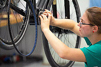 Profi-Werkstätten leiden unter Kehrseiten des Velobooms. Eine Velomechanikerin arbeitet an einem Fahrrad. 