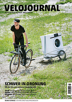 Ein Mann zieht mit dem Velo einen Anhänger