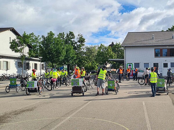 Kinder stehen mit Fahrrädern auf einem Pausenplatz. 