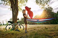 Tipps draussen schlafen auf der Velotour. Eine Frau in Fahrradbekleidung steht neben einer Hängematte.