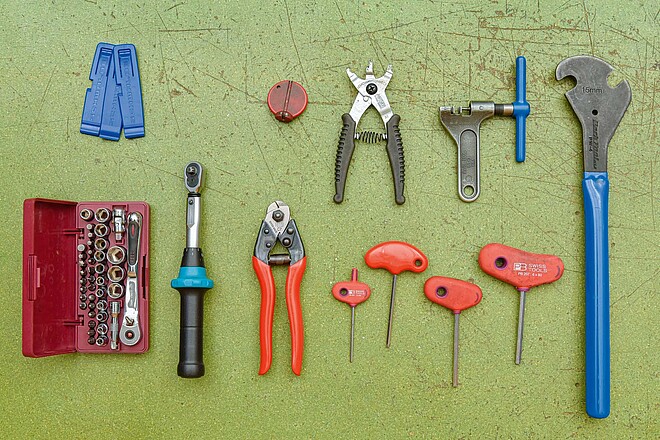 Viele Werkzeuge liegen auf einer Werkbank ausgebreitet da.