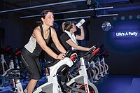 Zwei Frauen auf Spinning Bikes im Fitness Studio 