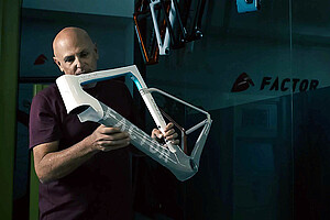 Ein Mann hält einen Rennrad-Rahmen in der Hand.