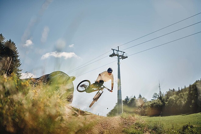 Biketrail Weissenstein. Ein Bike springt mit seinem Bike über einen Hügel.