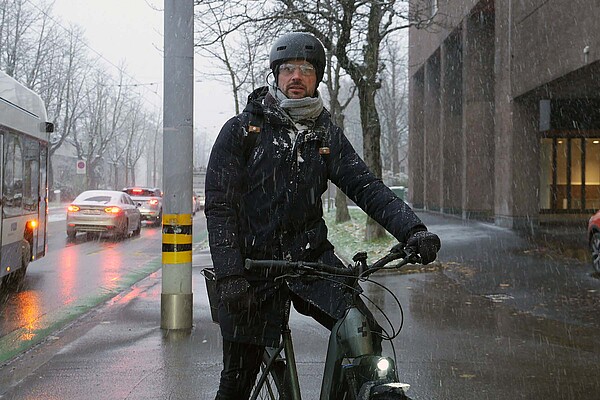 Radfahren im Winter. Ein Mann mit Winterjacke, Helm und Brille sitzt auf dem E-Bike.