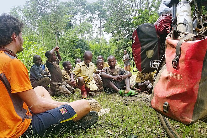 Film anderswo, alleine in Afrika. Ein Mann sitzt am Boden auf einer Wiese. 