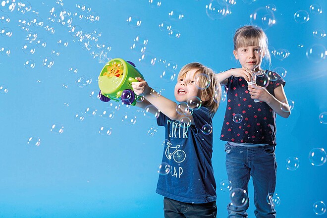 Als Familie lassen sich auf zwei  Rädern schöne Erlebnisse sammeln. Kinder spielen mit Seifenblasen.