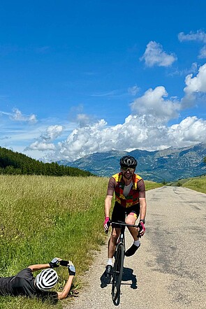 Fotostopp. Eine Person liegt am Boden, um einen Radfahrer zu fotografieren.