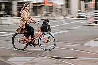 Eine Frau fährt mit dem Fahrrad durch die Stadt.