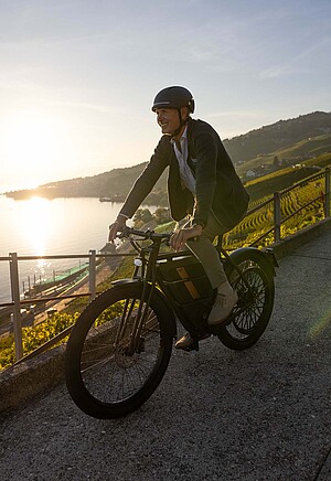 Motosacoche E-Bike. Ein Mann in Businesskleidung fährt auf einem E-Bike.