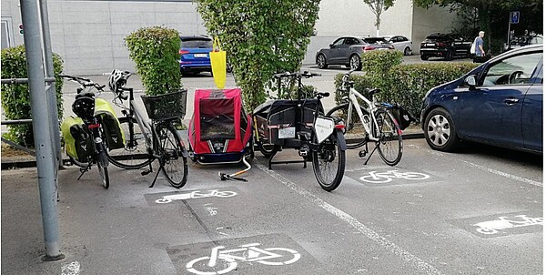 hinter dem Coop Lenzburg stehen Cargobikes und ein Veloanhänger