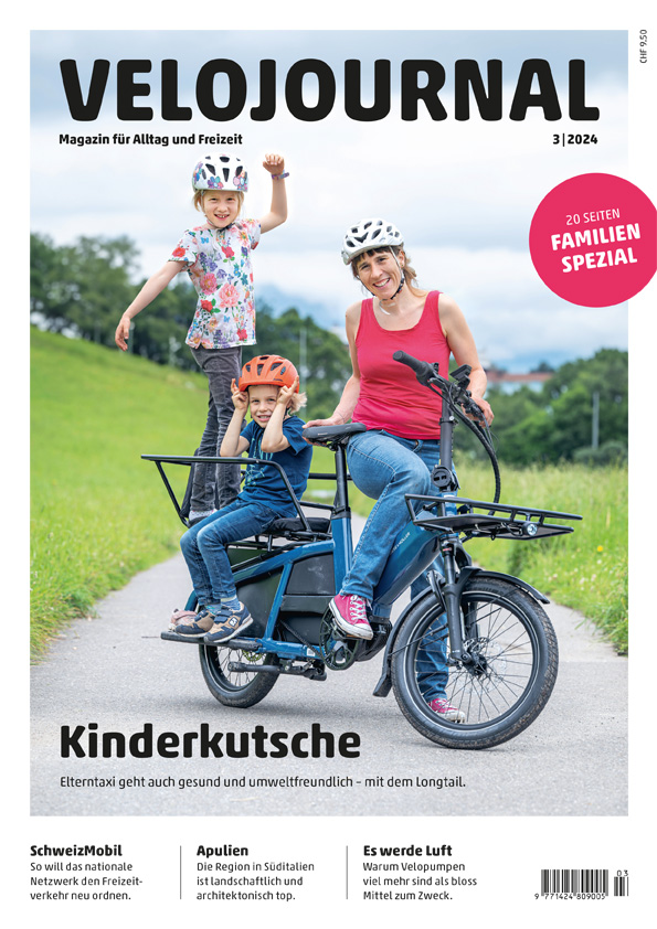 Velojournal 3-2024. Eine Frau steht mit einem Longtail auf der Strasse. Zwei Kinder sitzen hinten auf dem Fahrrad.